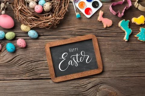 Colorful easter eggs and brushes on wooden table. Top view with copy space Stock Photos