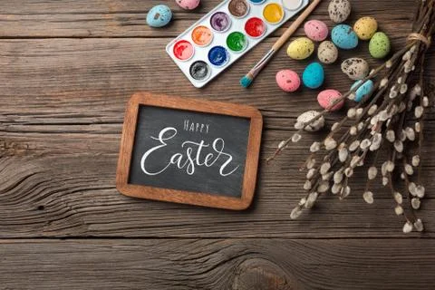 Colorful easter eggs and brushes on wooden table. Top view with copy space Stock Photos