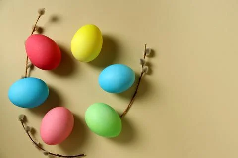 Colorful Easter eggs arranged on a plain surface with branches and catkins Stock Photos
