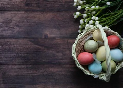 Colorful Easter eggs in a basket on the background of a wooden table, next to Foto stock