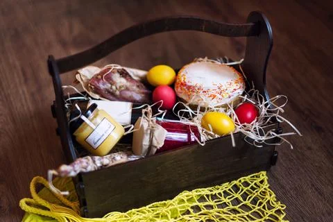 Colorful easter eggs in a basket with cake, red wine, hamon or jerky and dry  Stock Photos