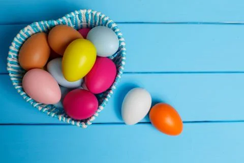 Colorful easter eggs in the basket isolated on a blue background Stock Photos