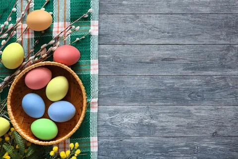 Colorful easter eggs in basket on rustic wooden table Stock Photos