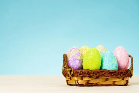 Colorful easter eggs in basket on table on blue background Stock Photos
