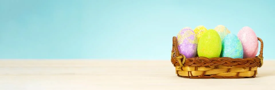 Colorful easter eggs in basket on table on blue background Stock Photos