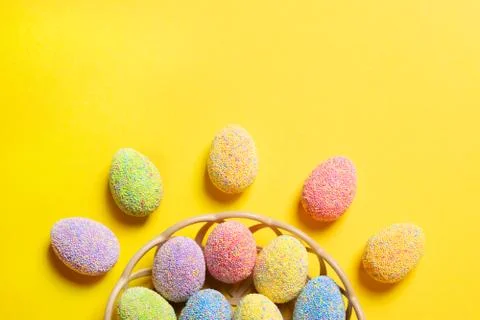 Colorful easter eggs in basket on yellow background. Stock Photos