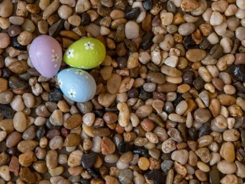 Colorful Easter eggs on bed of pebbles Stock Photos