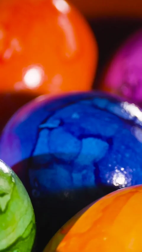 Colorful Easter eggs being dipped in vibrant dyes at a spring celebration with Stock Footage 317781927