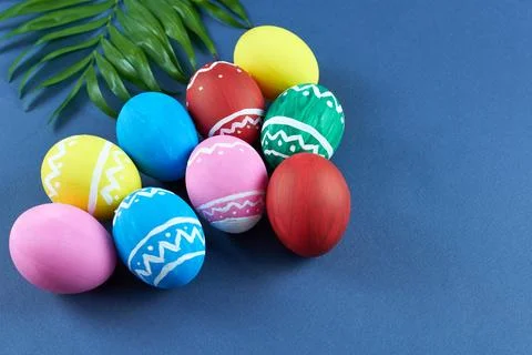 Colorful Easter eggs on a blue background with a green twig. Stock Photos