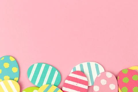 Colorful easter eggs bottom border on a bright pink background. Flat lay cele Stock Photos
