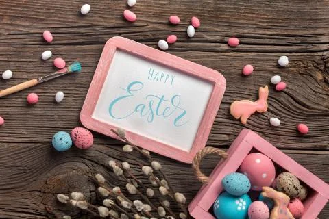 Colorful easter eggs in box and flowers on table. Top view with copy space. Stock Photos