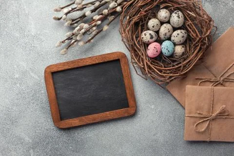Colorful easter eggs in box and flowers on table. Top view with copy space Stock Photos