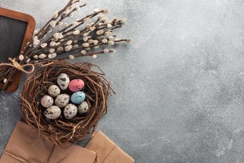 Colorful easter eggs in box and flowers on table. Top view with copy space Stock Photos