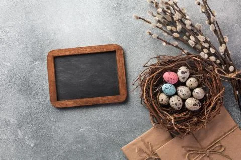 Colorful easter eggs in box and flowers on table. Top view with copy space Stock Photos