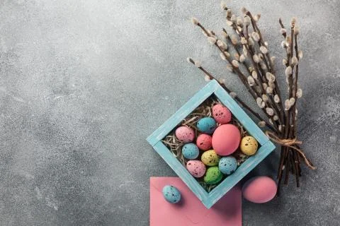 Colorful easter eggs in box and flowers on table. Top view with copy space. Stock Photos