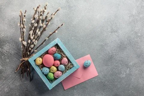 Colorful easter eggs in box and flowers on table. Top view with copy space. Stock Photos