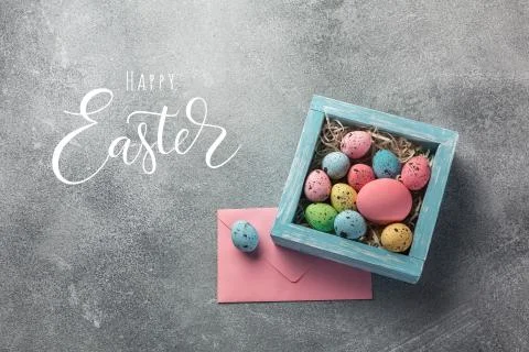 Colorful easter eggs in box and good wishes on table. Top view with copy spac Stock Photos