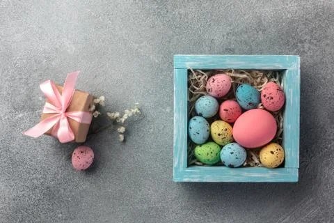 Colorful easter eggs in box and gift on table. Top view with copy space. Stock Photos