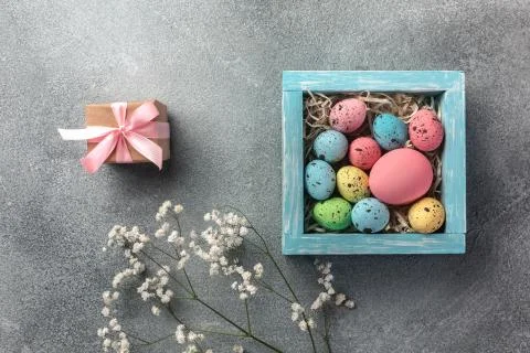 Colorful easter eggs in box and gift on table. Top view with copy space. Stock Photos