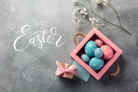 Colorful easter eggs in box and gift on table. Top view with copy space. Stock Photos