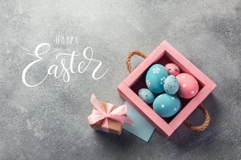 Colorful easter eggs in box and gift on table. Top view with copy space. Stock Photos
