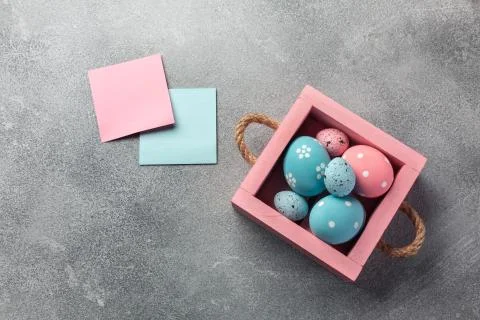 Colorful easter eggs in box and gift on table. Top view with copy space. Stock Photos