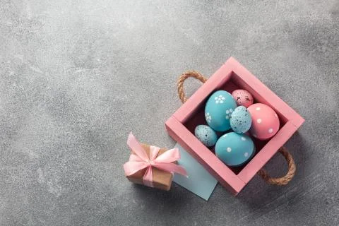Colorful easter eggs in box and gift on table. Top view with copy space. Stock Photos