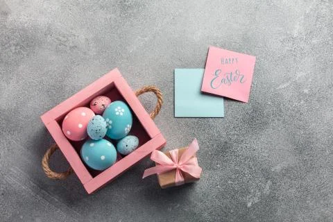 Colorful easter eggs in box and gift on table. Top view with copy space. Stock Photos