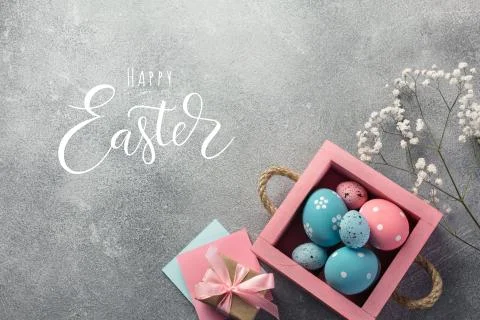 Colorful easter eggs in box and gift on table. Top view with copy space. Stock Photos
