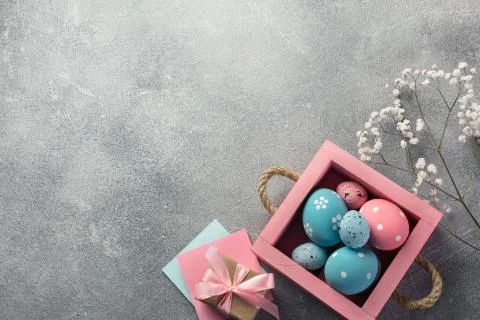 Colorful easter eggs in box and gift on table. Top view with copy space. Stock Photos