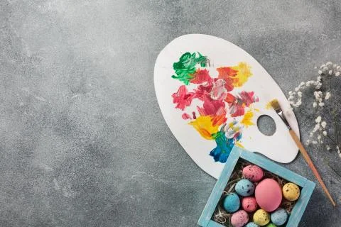 Colorful easter eggs in box and paints on table. Top view with copy space. Stock Photos