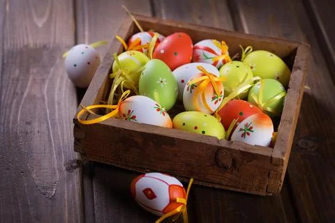 Colorful easter eggs in box on dark wooden background. Easter background. Stock Photos