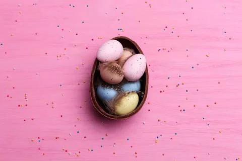 Colorful easter eggs in a brown basket on pink background Stock Photos