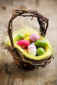 Colorful easter eggs in brown basket, shallow focus Stock Photos