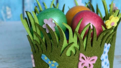 Colorful Easter Eggs In A Grass Basket With Easter Rabbits On A Blue Wooden Back Stock Footage 126589663