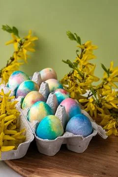 Colorful Easter eggs on a green background next to yellow flowers Stock Photos