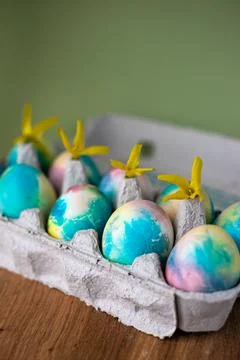 Colorful Easter eggs on a green background next to yellow flowers Stock Photos