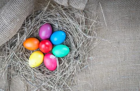 Colorful easter eggs in hay on sackcloth backround Stock Photos