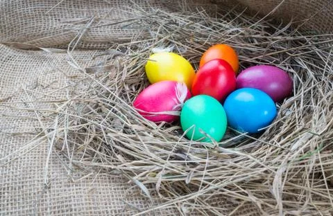 Colorful easter eggs in hay on sackcloth background Stock Photos