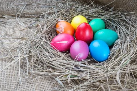 Colorful easter eggs in hay on sackcloth background Stock Photos