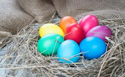 Colorful easter eggs in hay on sackcloth background Stock Photos