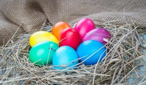 Colorful easter eggs in hay on sackcloth background Stock Photos
