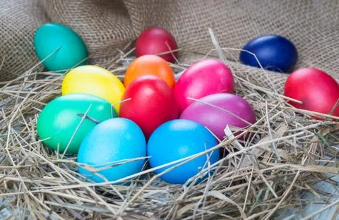 Colorful easter eggs in hay on sackcloth background Stock Photos