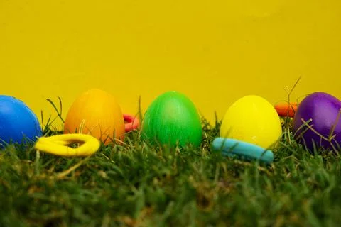 Colorful Easter Eggs Hidden in Grass with Yellow Background Stock Photos