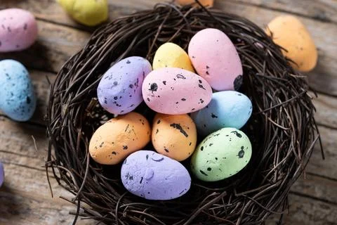 Colorful Easter eggs inside a nest on wooden table Stock Photos