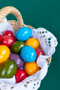 Colorful Easter eggs inside straw wicker on green background Stock Photos