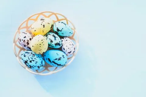 Colorful Easter eggs lie in a round basket on a blue background. the view fro Stock Photos