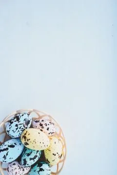 Colorful Easter eggs lie in a round basket on a blue background. the view fro Stock Photos