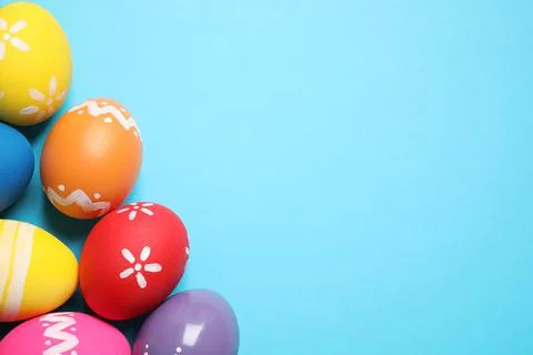 Colorful Easter eggs on light blue background, flat lay. Space for text 库存照片