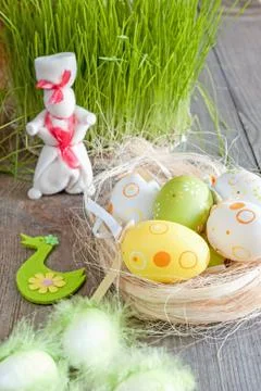 Colorful Easter eggs lying on the table next to the green of fresh grass an.. Stock Photos